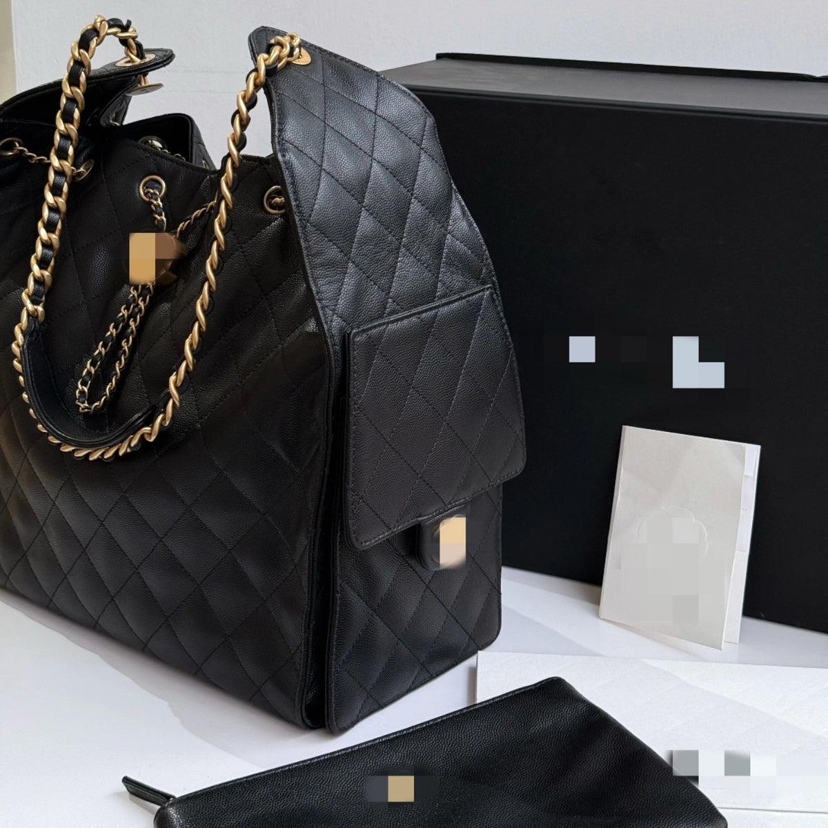 Bolsa C preta elegante, com alça de ombro em metal dourado e amplo espaço interno